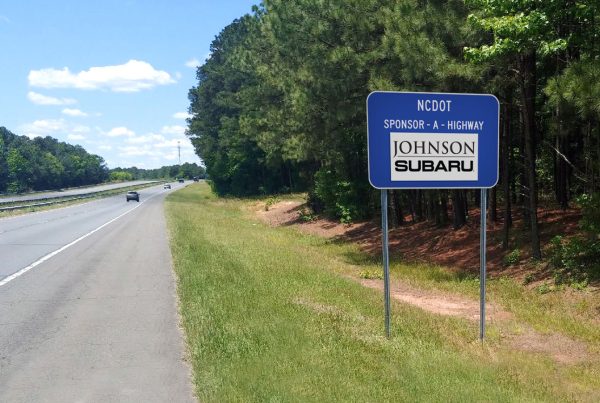 Johnson Subaru Sponsor Panel alongside a clean highway with car in the distance